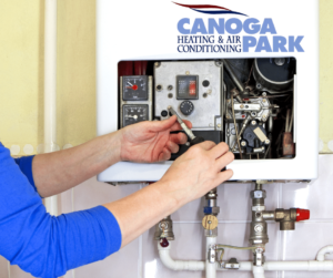 This photo for the blog post on Signs That You Need to Schedule a Heating Repair shows a tech repairing a unit.